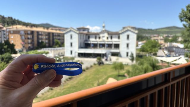 Custom bilingual Mediband medical alert bracelet held against the town of Estella on the Camino de Santiago