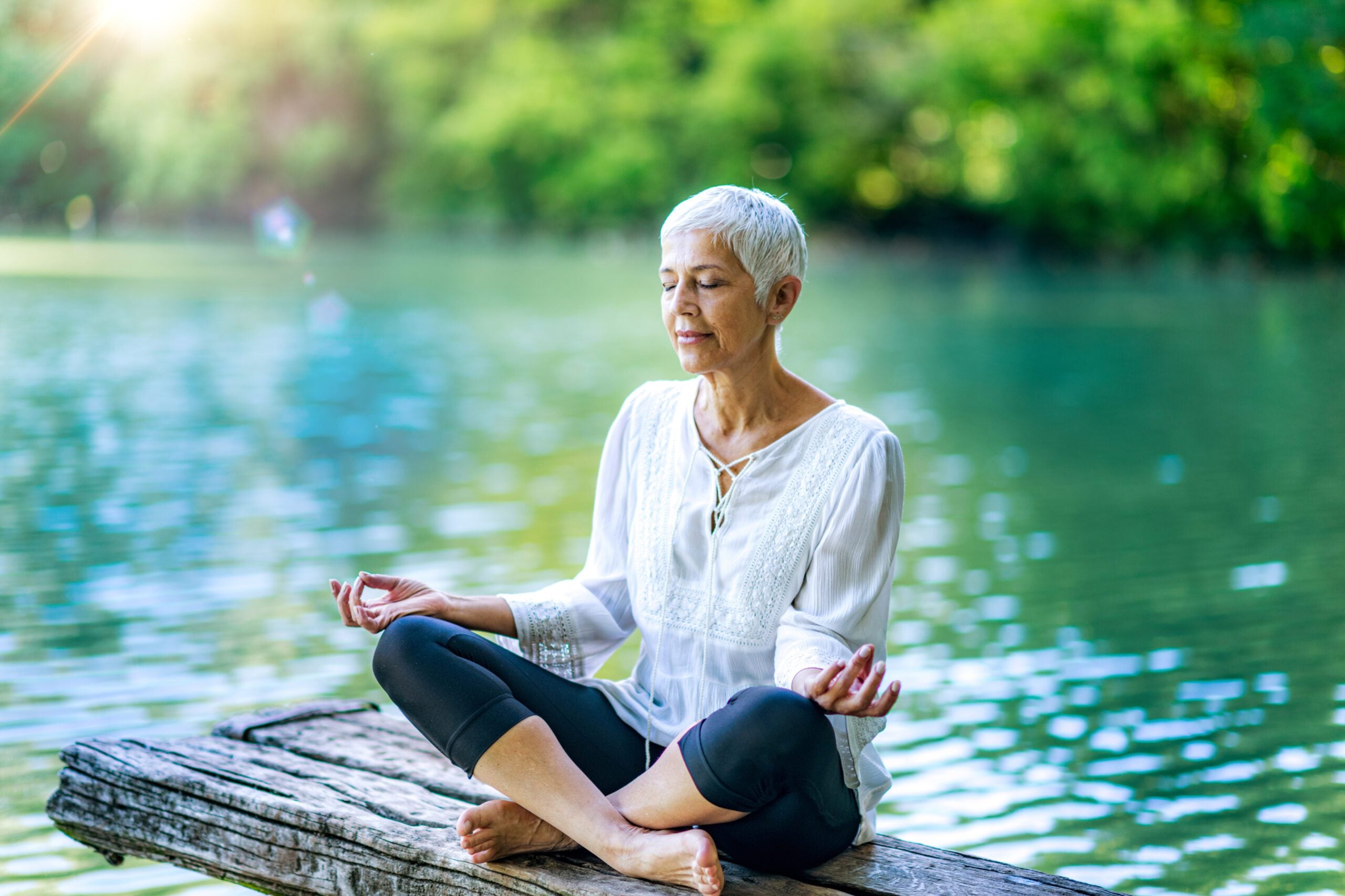 Person meditating by the water to manage chronic illness stress