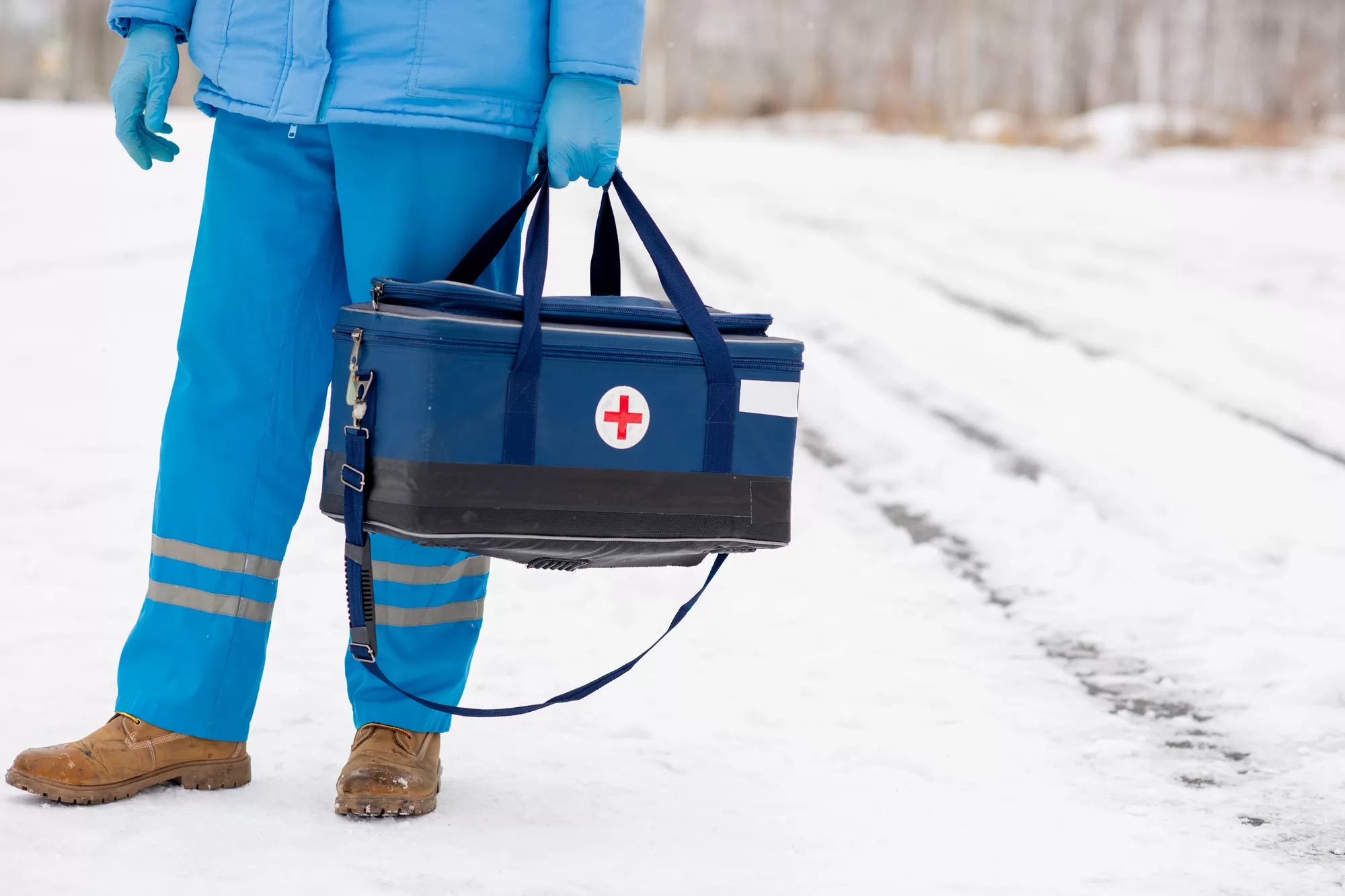 Young paramedic in blue workwear holding first aid kit — what to do in a medical emergency — Mediband