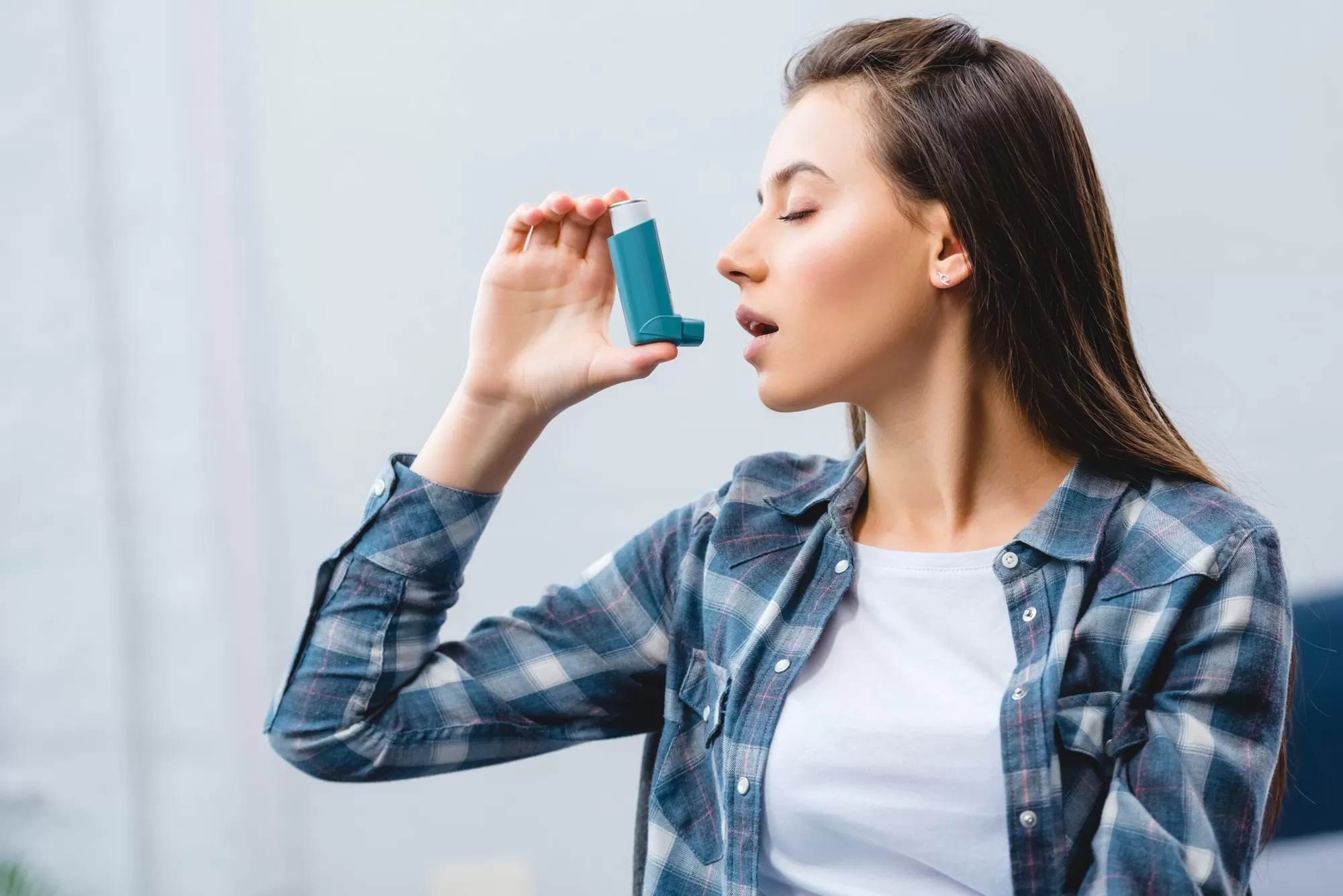 Young woman correctly using an asthma inhaler during an attack