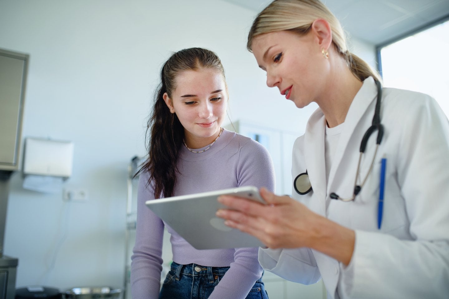 Female doctor explaining a diagnosis to a teenage girl in a bright clinic — epilepsy medical ID consultation Female doctor explaining a diagnosis to a teenage girl in a bright clinic — epilepsy medical ID consultation
