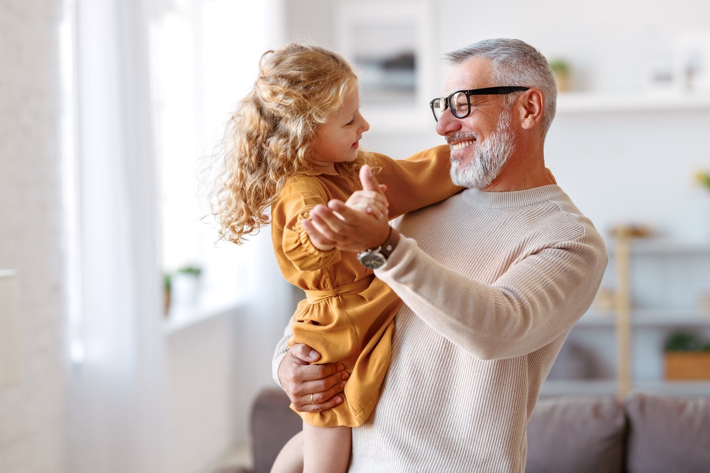Grandfather and granddaughter dancing at home — pacemaker recipient enjoying everyday life with their family