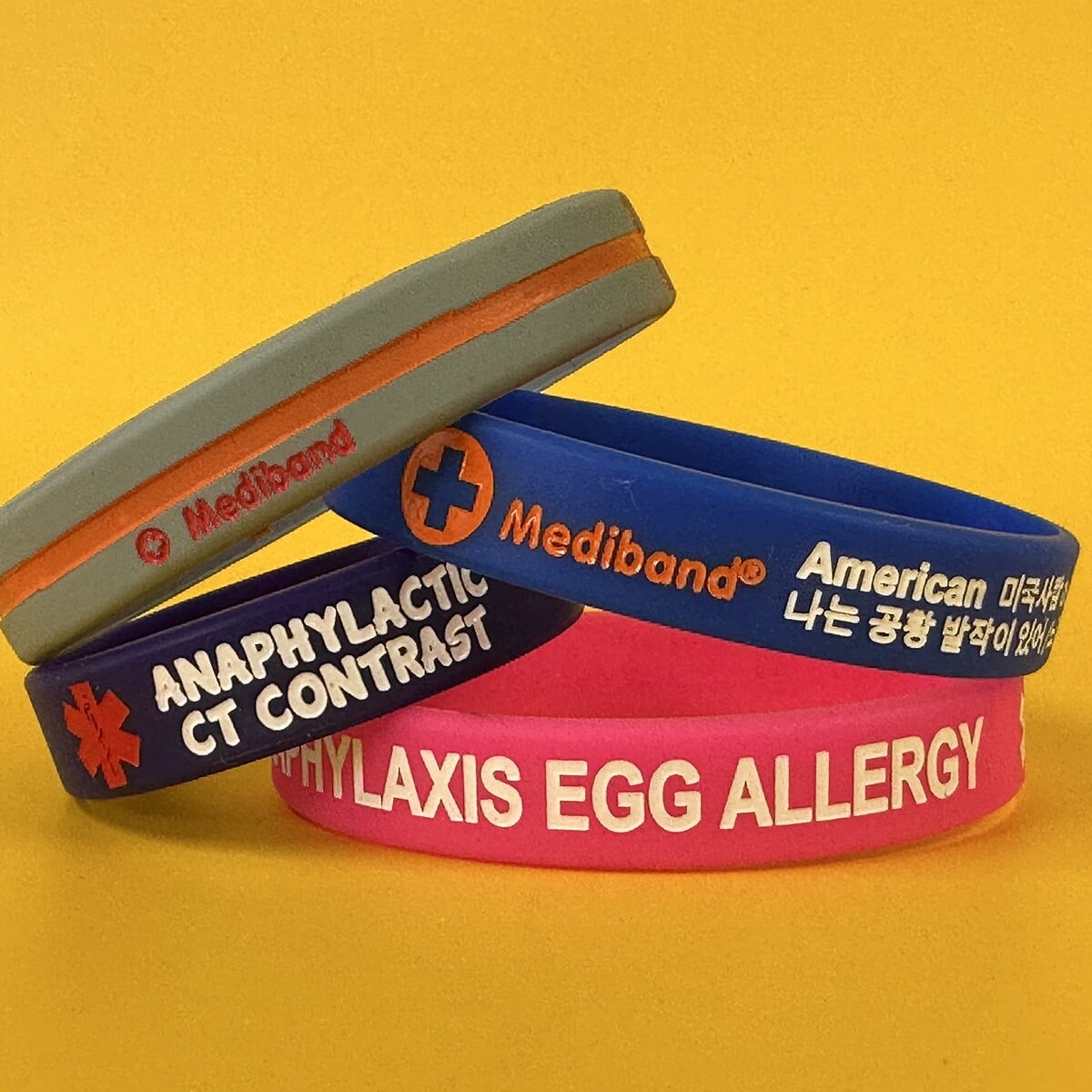 A stack of multilingual Mediband silicone bracelets including English, Korean, Spanish and Japanese engravings — Mediband's range of language options for international travellers